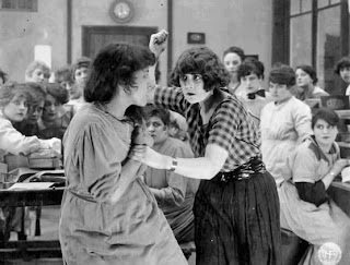 Annie Bos (right) as Carmen, fights in cigarette factory.