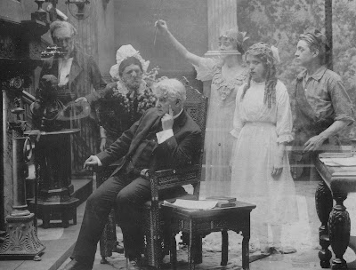 Prologue from A Good Little Devil - David Belasco (seated) as wraiths of his characters appear via double-exposure.  Others in the picture (L to R):  Edward Connelly, William Norris (as old woman), Wilda Bennett, Mary Pickford, Ernest Truex.